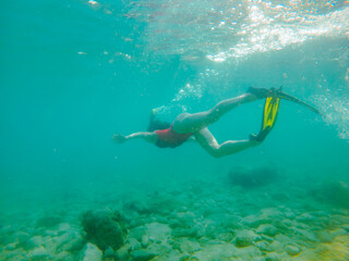 woman in red swimming suit underwater with snorkeling mask and flippers
