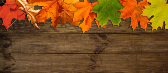 Obraz premium Autumn leaves over wooden background with copy space