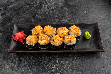 Set of baked sushi rolls with wasabi and ginger on a black background. Japanese oriental cuisine