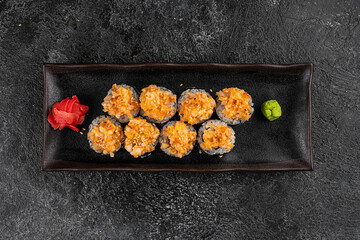 Set of baked sushi rolls with wasabi and ginger on a black background. Japanese oriental cuisine
