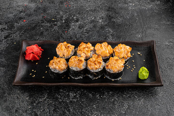 Set of baked sushi rolls with wasabi and ginger on a black background. Japanese oriental cuisine