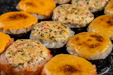 Set of baked sushi rolls with wasabi and ginger on a black background. Japanese oriental cuisine