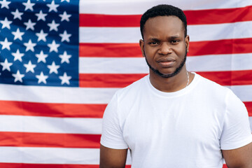 Portrait of handsome african american guy in a white t-shirt who's stands on USA flag background
