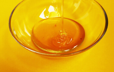 Close-up honey in a glass plate on a yellow background. Health and summer concept.