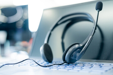 Obraz na płótnie Canvas Call center operator desktop. Close-up of a headset on a laptop. Help desk. Workplace of a support service employee. Headphones with a microphone for voip on a computer keyboard.