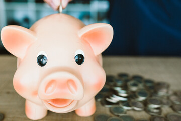 Saving, female hand putting a coin into piggy bank.