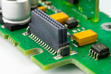 Macro photo of the integrated circuit on a green printed circuit board, visible resistors,...