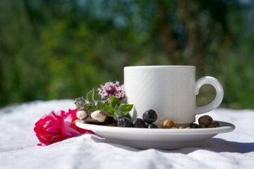 Coffee composition  with  white cup    of herbal coffe with herb , beans of coffe,  Chocolate,  berry, mint, flower on  linen tableclothtable