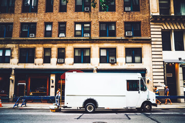 Fototapeta premium White van automobile for relocation and delivery parked on city street near building, cargo of logistic company with moc up area for distribution and shipping corporate name or logo in downtown
