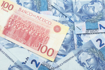 A close up image of a one hundred Mexican peso bank note with Brazilian two reais bank notes in macro