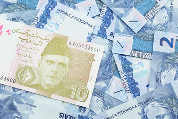 Fototapeta premium A close up image of a gray and pink ten Pakistani rupee bank note with Brazilian two reais bank notes in macro