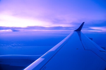 wing of aircraft flying at sunset