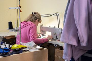 Girl sews on a professional sewing machine in the workshop