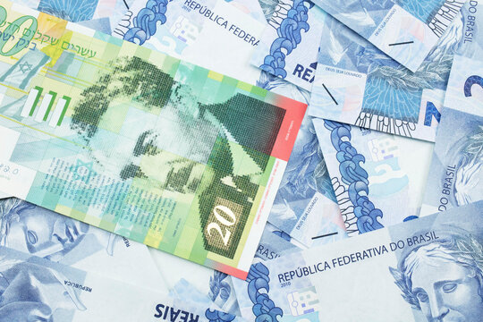 A close up image of a twenty shekel bank note from Israel on a background of Brazilian two reais bank notes in macro