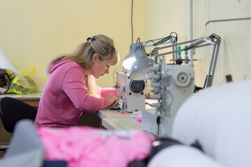 Worker in sewing workshop sews on a professional sewing machine