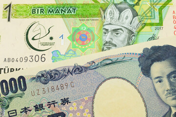 A macro image of a Japanese thousand yen note paired up with a green and yellow one manat note from Turkmenistan.  Shot close up in macro.