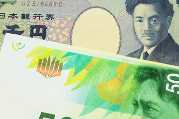 A macro image of a Japanese thousand yen note paired up with a green and white fifty shekel bank note from Israel.  Shot close up in macro.