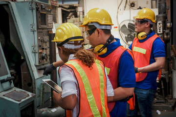 Engineer with Female mechanical worker with yellow safety helmet checking on production in a...