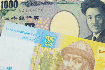 A macro image of a Japanese thousand yen note paired up with a blue, white and yellow one hyrvnia bank note from Ukraine.  Shot close up in macro.