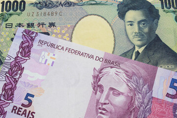 A macro image of a Japanese thousand yen note paired up with a pink and purple five real bank note from Brazil.  Shot close up in macro.