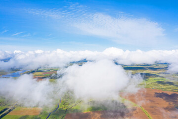 Flying through the fluffy clouds layers. Camera above ground. Amazing soft white clouds moving slowly on the clear sky
