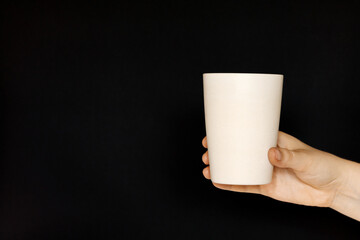 Bamboo cup in hand on a black background.