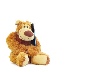 Teddy bear with a mobile phone isolated on a white background.