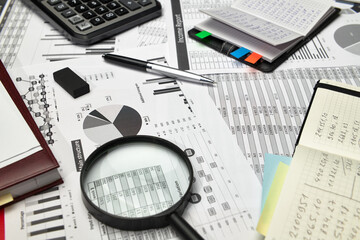 Top view of office employee's desk - work with financial reports, analysis and accounting, tables and graphs, various office items for bookkeeping