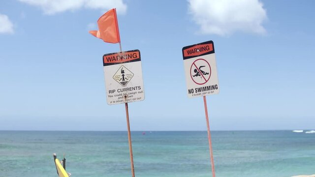 Ocean safety warning signs, red flag blowing in wind. Slow motion.