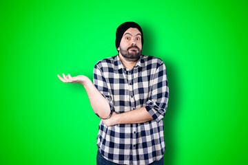 Closeup photo of young handsome man isolated on green studio background dressed casually, looking...
