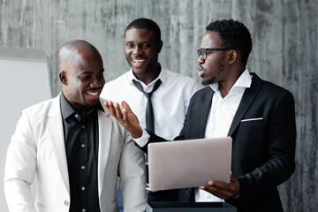 Black colleagues African-American in suits in the office animatedly discussing a new startup...