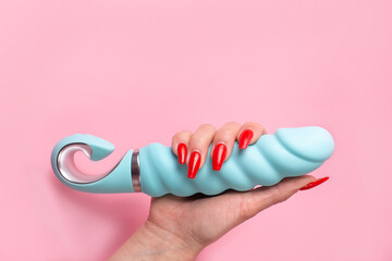 Dildo in hand on a pink background, sex toy