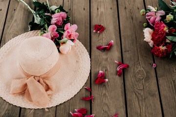 Straw hat with peonies. Photo of a summer still life.