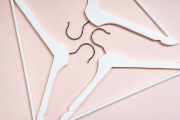 Top view of white wooden hangers on a pink background. The concept of the crisis of the fashion industry, the closure of shops. The trend of conscious consumption, eco-friendly anti-consumerism. 