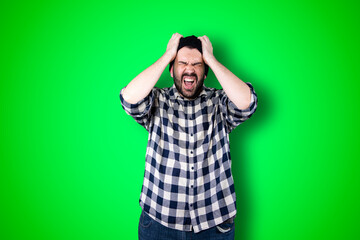 Portrait of a puzzled bearded man holding hands on his head isolated over chroma background