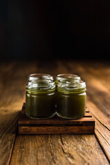 Green colored alcoholic shooters, or shot drinks on wooden table, copy space