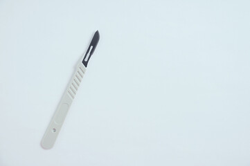 A disposable plastic surgical scalpel with a blade on  white background.