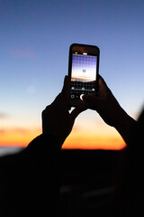 camera in hand in front of a sunset