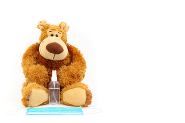 Toy bear with antiseptic and medical mask isolated on a white background.