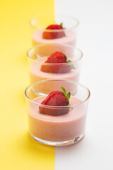 Strawberry panna cotta in glass cup and white and yellow background