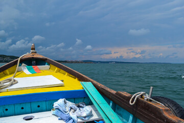 Obraz premium A small colourful wooden boat in sea on sunset