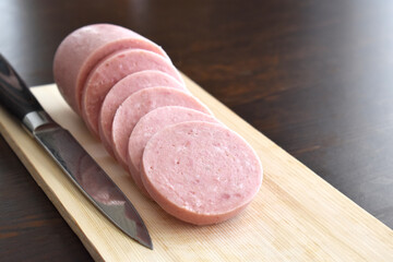 Greek Parizaki pork stick slices on the cutting board with a knife on the right side.  Selective focus.  Copy space is on the right side. 