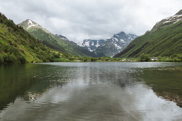 Ripple reflection in the alpine lake Tumanly Kol' with high snowy peaks and storm clouds in the background, Teberda Nature Reserve in Caucasus Mountains