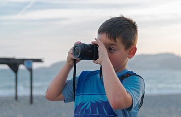 Young boy photographer taking pictures on the beach.