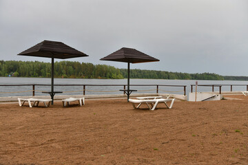 sandy beach with umbrellas and sunbeds on the banks of the river
