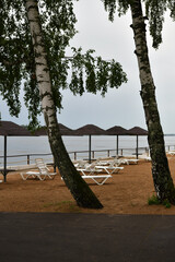sandy beach with umbrellas and sunbeds on the banks of the river
