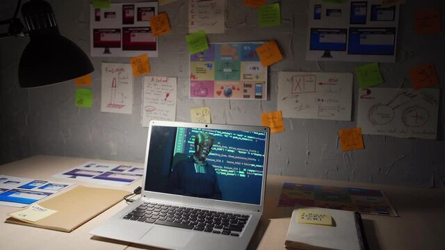 Open laptop computer with online computer programming lesson given by senior teacher on screen placed on desk at home surrounded by notepads, sticky notes and papers and lit by lamp at night