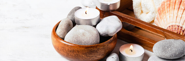 Spa composition with essential oil, stones, shell, soft towel, candle. Aromatherapy and relax, atmosphere of serenity and relaxation. Close up, macro view. White wooden background, banner, copy space