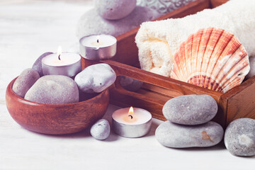 Spa composition with essential oil, stones, shell, soft towel, candle. Aromatherapy and relax, atmosphere of serenity and relaxation. Close up, macro view. White wooden background, tonned