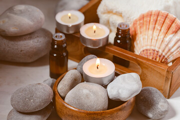 Fototapeta na wymiar Spa composition with essential oil, stones, shell, soft towel, candle. Aromatherapy and relax, atmosphere of serenity and relaxation. Close up, macro view. White wooden background, tonned